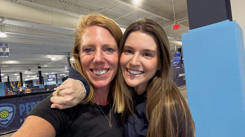 Two pickleball doubles partners arm in arm at a tournament, the partnership behind shared flow
